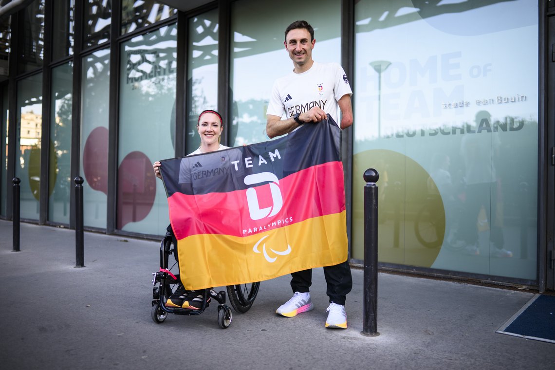 Die Sportler Edina Müller und Martin Schulz halten die deutsche Fahne.
