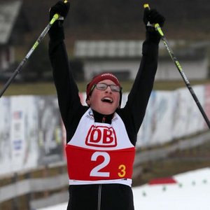 Para Ski Nordisch Langläufer überquert die Ziellinie und reißt die Arme hoch zum Zeichen als Zeichen des Sieges