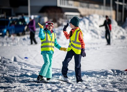 Zwei Sportlerinnen beim "High Five" auf Ski.