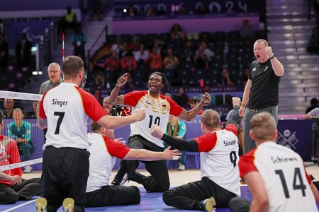 Die deutschen Sitzvolleyballer feiern mit ihrem Trainer einen Punkt im Spiel gegen den Iran. Foto: Mathias Schulz / DBS
