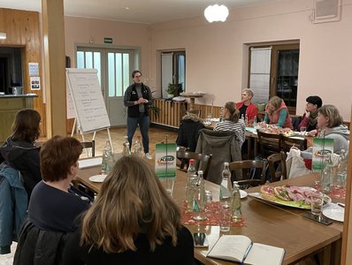 Bild vom Netzwerktreffen. Lydia Reis steht an einer Flip-Chart Tafel